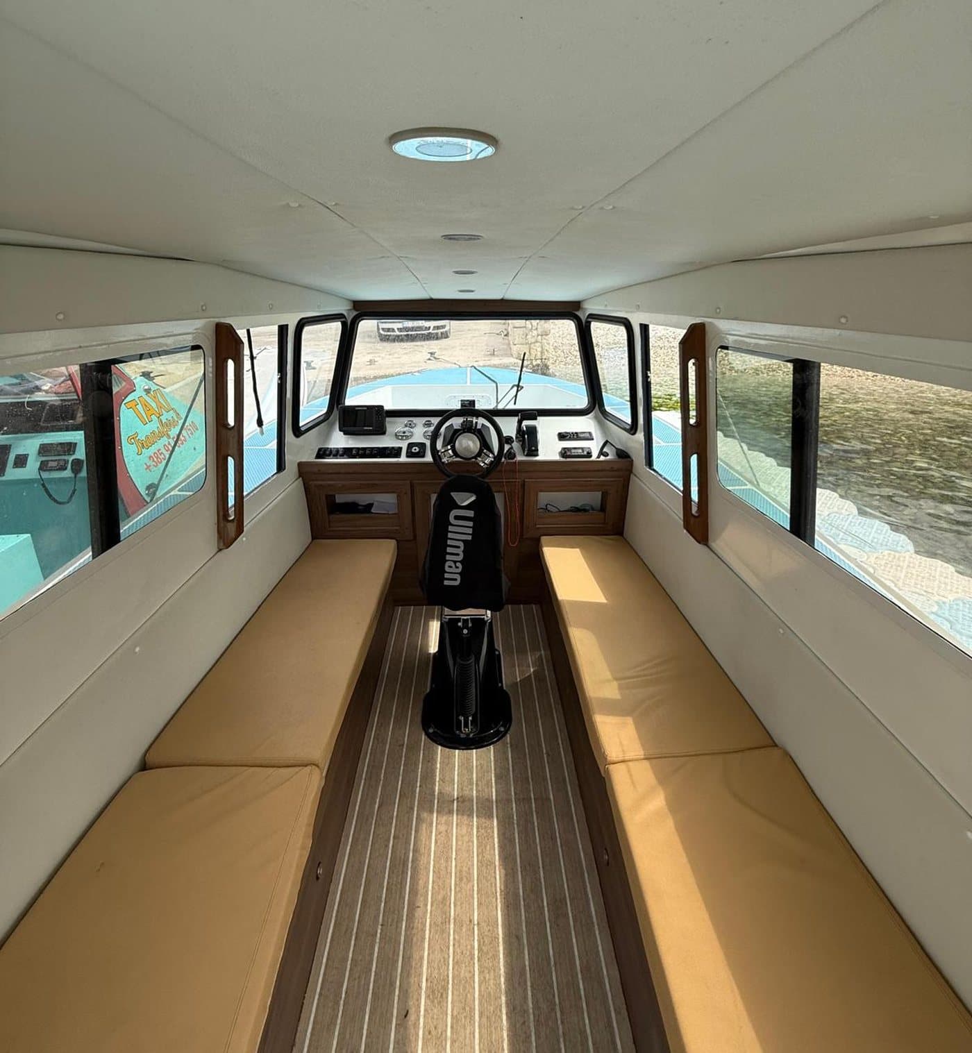 Inside the Navis Tours cabin — benches, teak-style deck and the helm