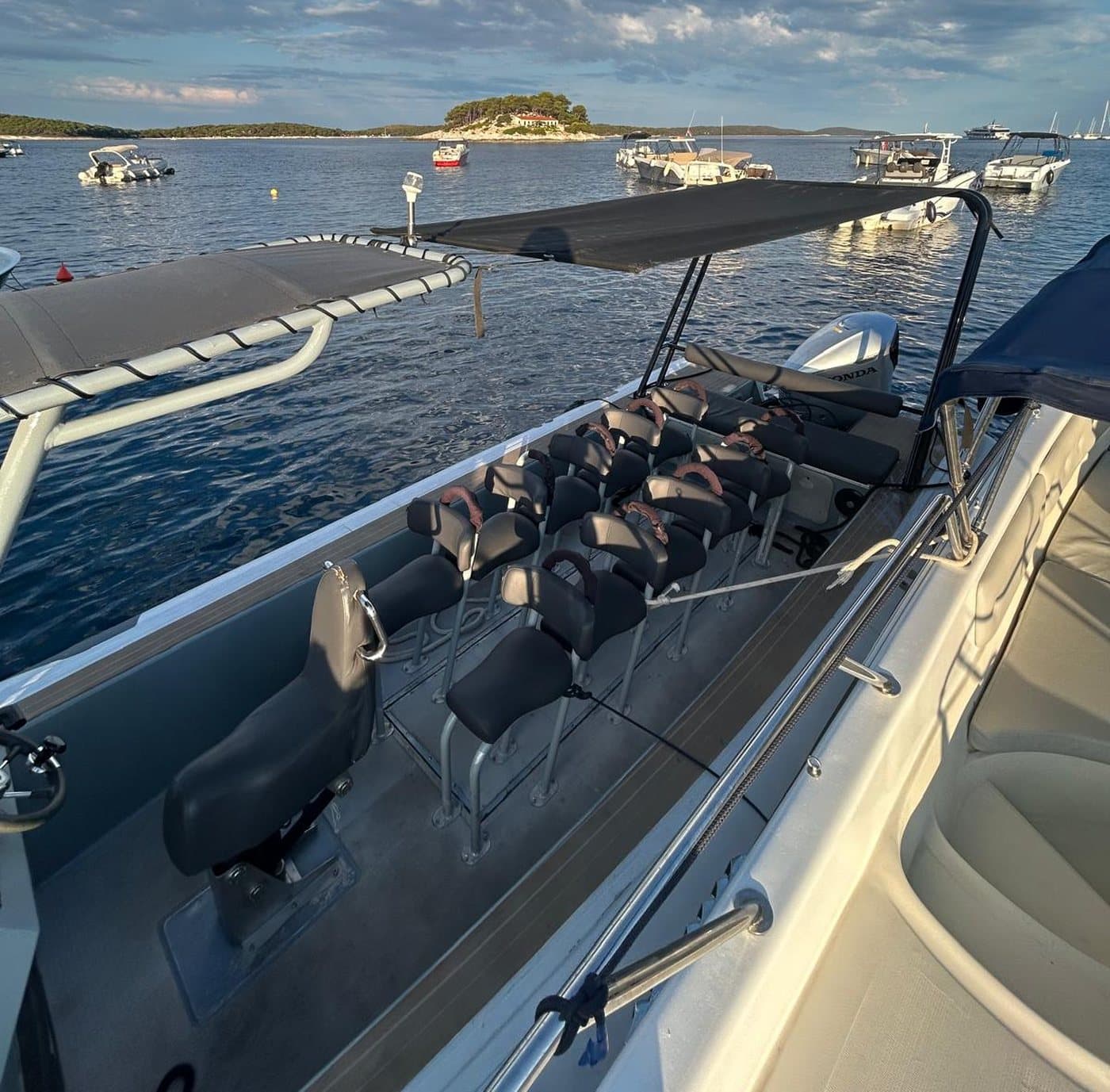 Aboard the open boat — rows of jockey seats under the canopy, the Pakleni Islands ahead