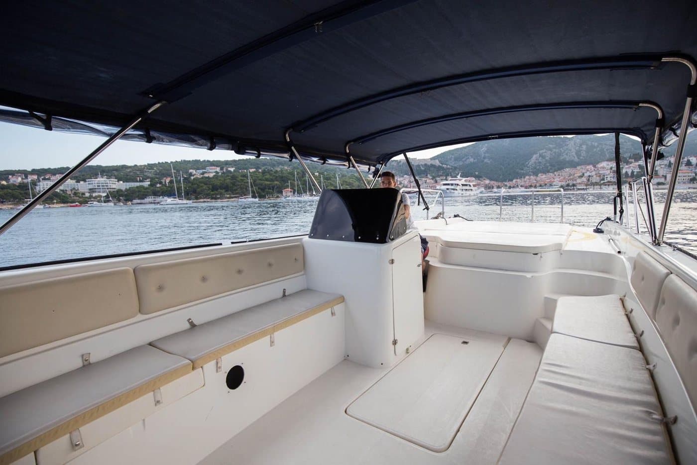 Aboard the launch — cushioned benches under the canopy, Hvar Town and the Fortica across the water