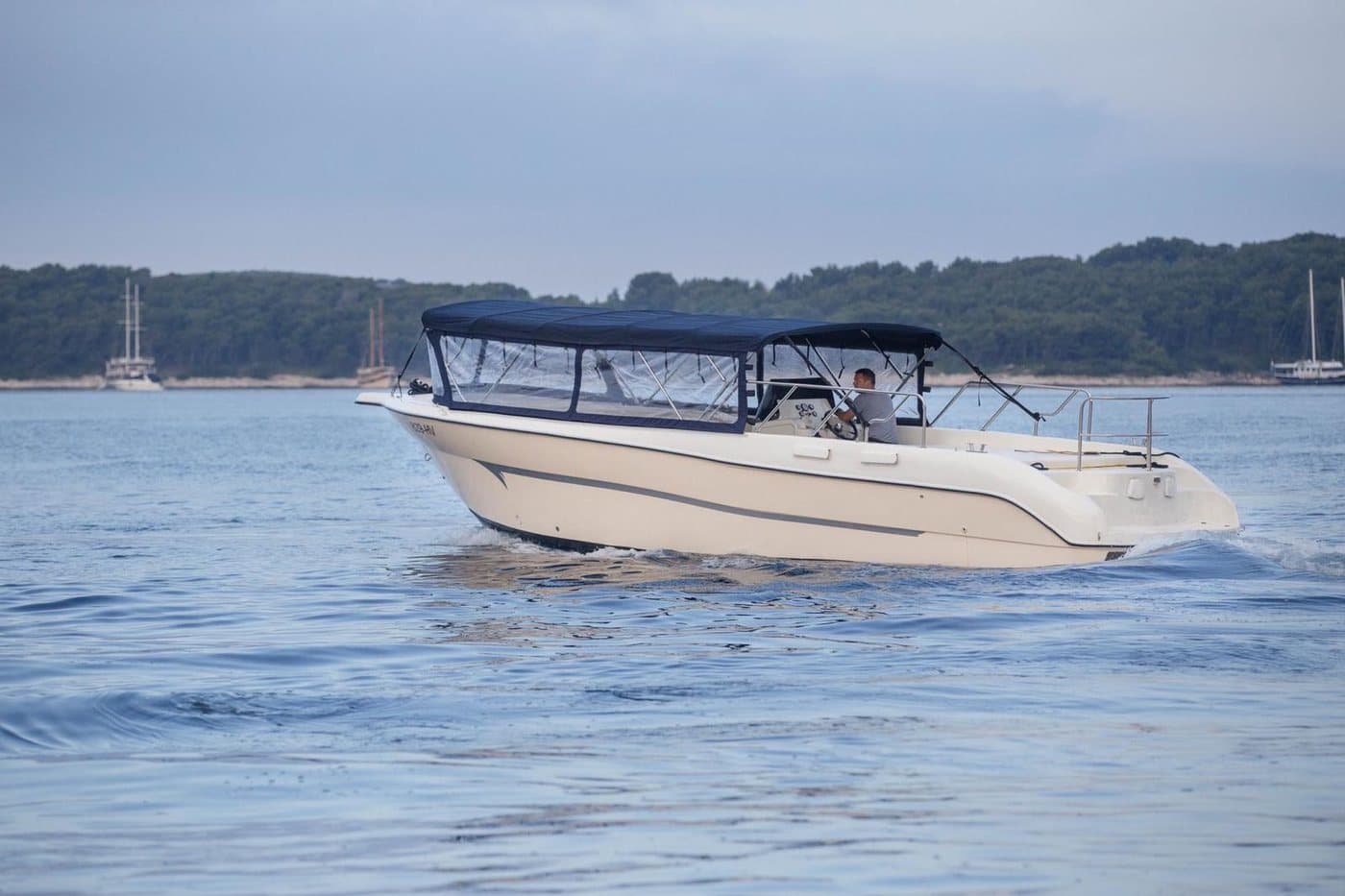 The Navis Tours launch under way off the Pakleni Islands — navy canopy over a white hull