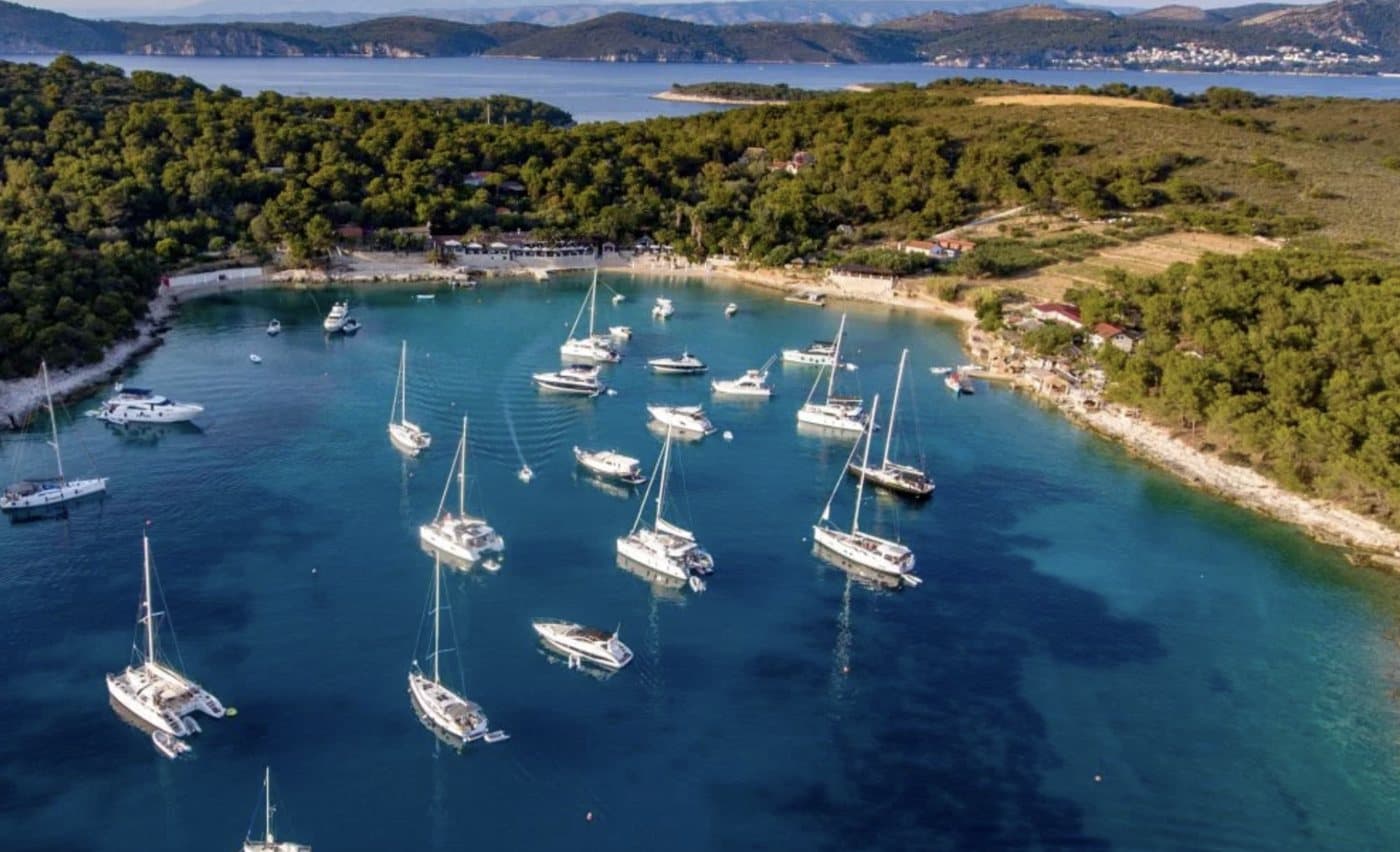 Vinogradišće Bay on Palmižana from above — yachts at anchor, the beach and its restaurants under the pines
